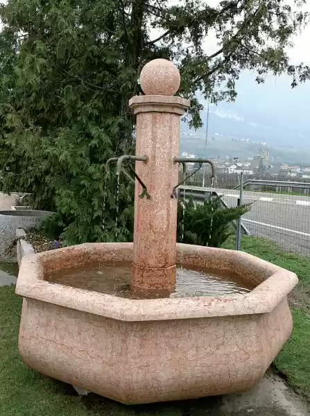 Großer Brunnen mit zentraler Säule aus rotem Kalkstein mit handgeschmiedeten Wasserausläufen