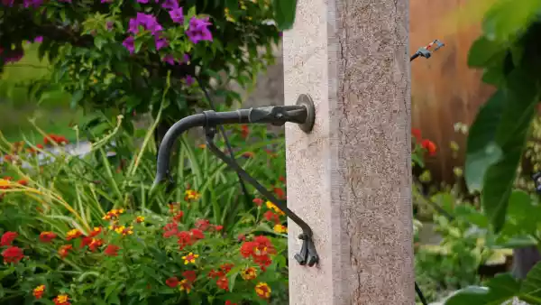 Handgeschmiedeter Wasserhahn aus Kupfer, auf Maß für diesen Brunnen mit Steinsäule aus Naturstein